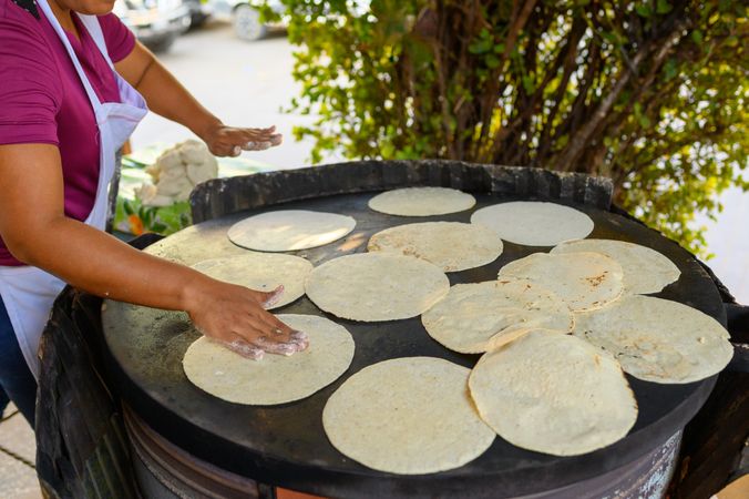 Woman cooking tasty tortillas on street