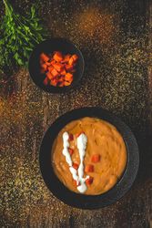 Orange cream soup and sliced carrot with green in bowls