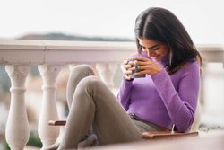 Female laughing outside on patio with a cosy warm drink