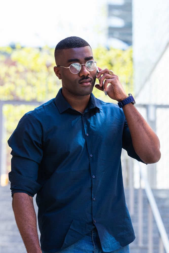 Serious Black male talking on cellphone in street