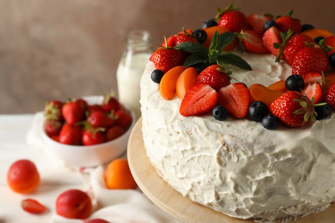 Composition with delicious berry cream cake against brown background. Tasty dessert