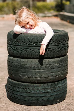 Little girl resting in stack of tires