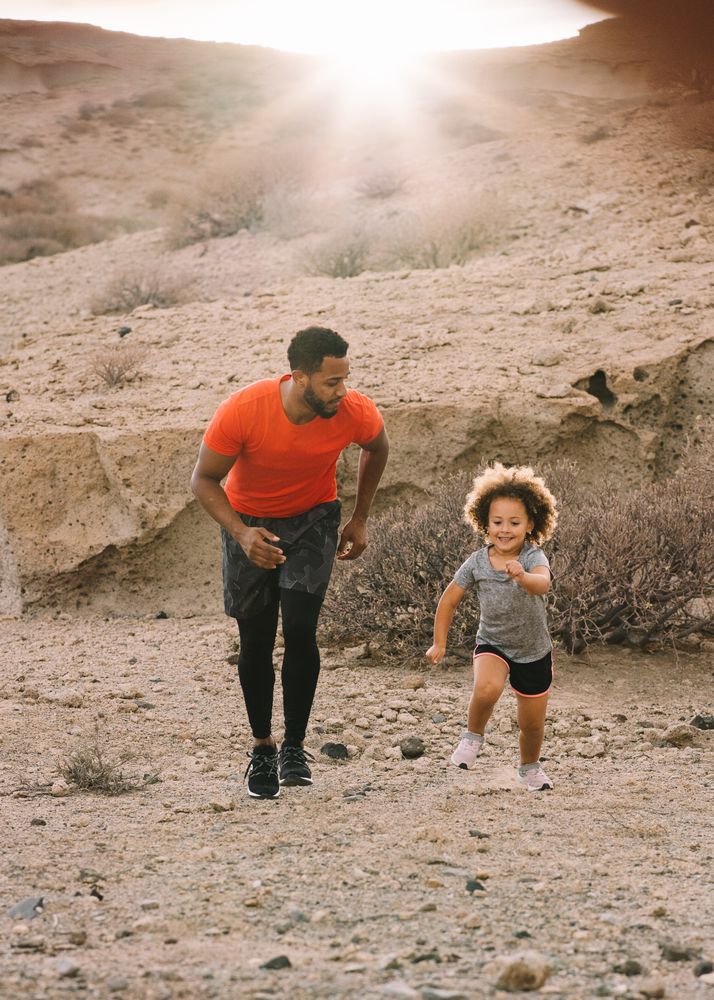 Black man jogging with toddler on nature
