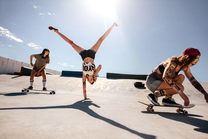 Woman doing a cartwheel at a skate park with friends behind her on skateboards