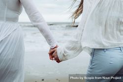 Two women holding hands standing on beach 4Nr8Z4