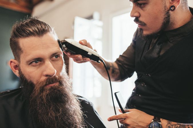 Hairstylist giving stylish haircut to client at barbershop