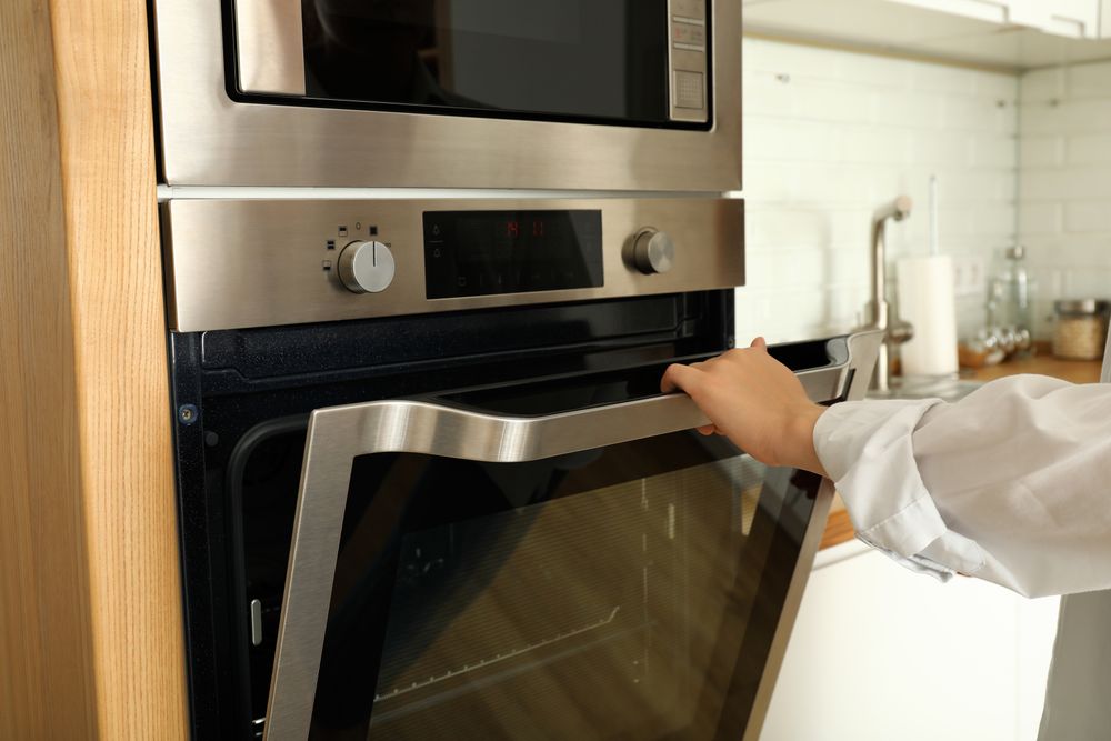 Young woman hand open modern oven in kitchen