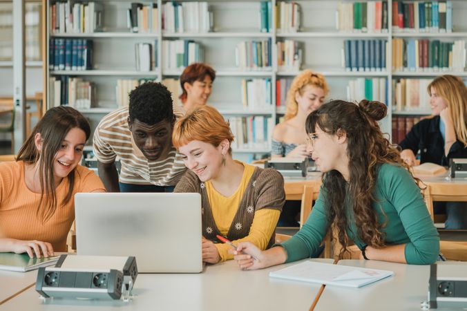 Diverse students discussing data on laptop