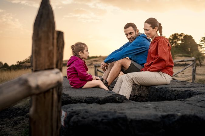 Family resting and talking together during a hike at sunset.