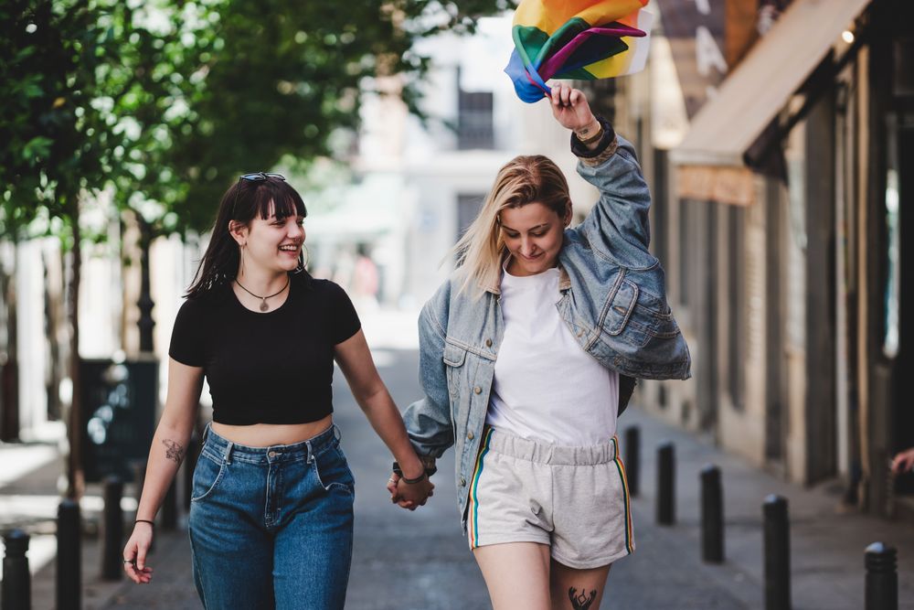 Lesbian couple with LGBT flag walking on street