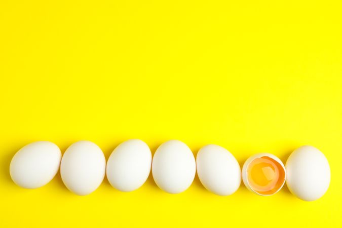Chicken eggs with half yolk on color background, space for text