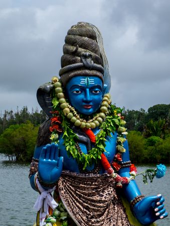Blue sacred statue on cloudy day by the lake