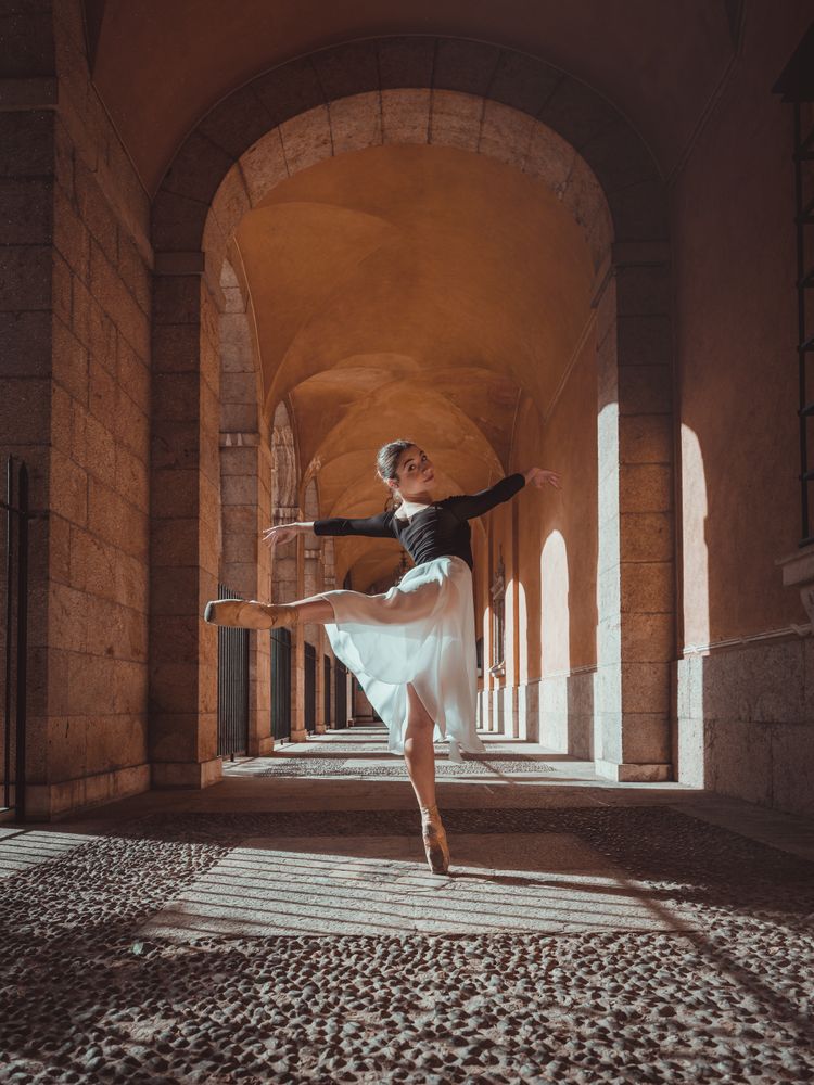 Graceful ballerina in tutu performing arabesque position in arch