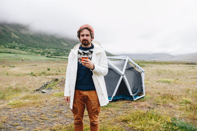Man waking up from tent with coffee