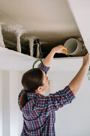 Woman placing tube for kitchen hood installation