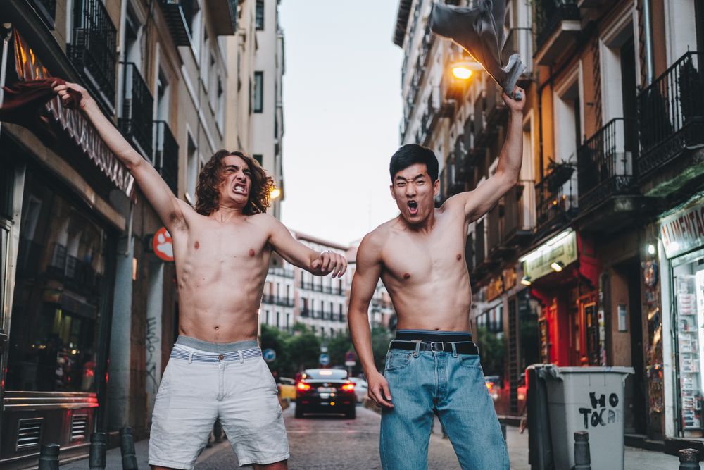 Rebellious shirtless multiracial men shouting while standing together on city street
