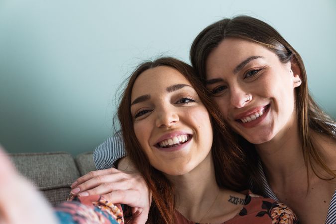 Smiling women hugging and taking selfie on smartphone