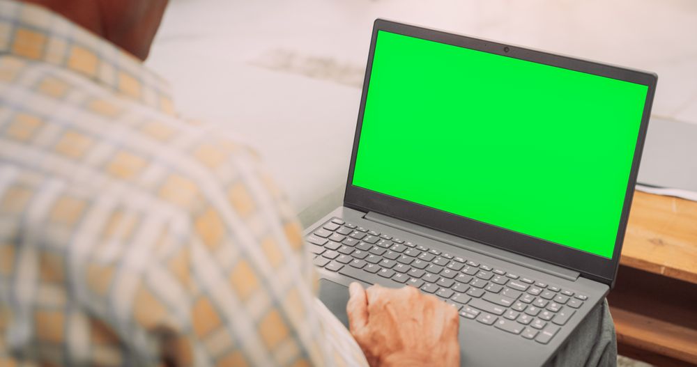 Over-the-Shoulder View of Mature Indian Gentleman Using Laptop with Green Screen: Doing Remote Work, Virtual Meetings