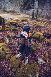 Bored female tourist resting on rock at autumn forest