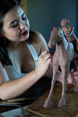 Young Asian woman working on sculpture inside