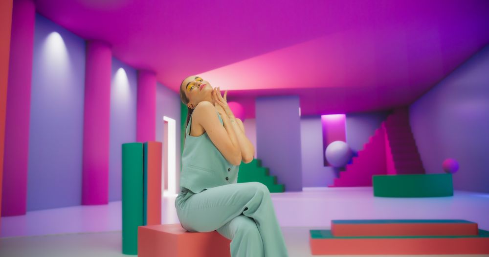 Portrait of Young Woman Sitting in Geometric Abstract Environment, Dancing with Hypnotic Graceful Movements. Fashionable Female Dancer Practicing Her Routine in Colorful Studio
