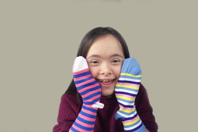 Young child playing with striped socks over her hands
