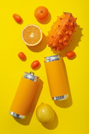 Tropical fruit and tin cans on yellow background, top view