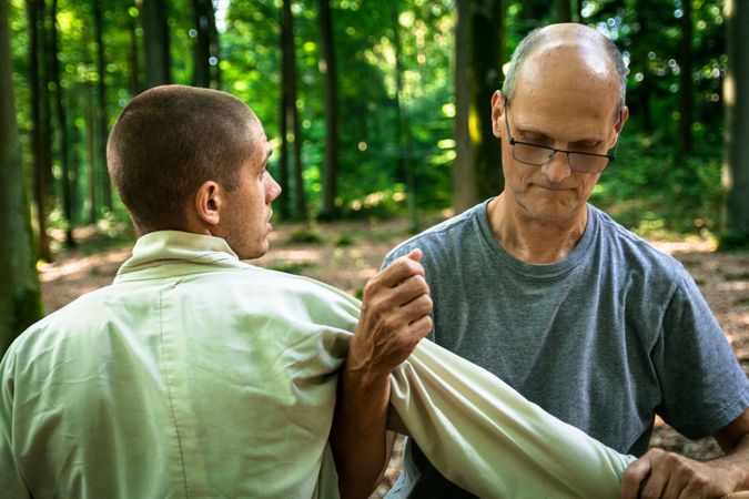 Mature man training martial arts student in forest