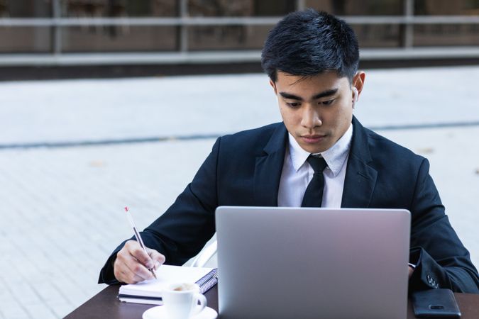 Serious male entrepreneur in suit working in cafe