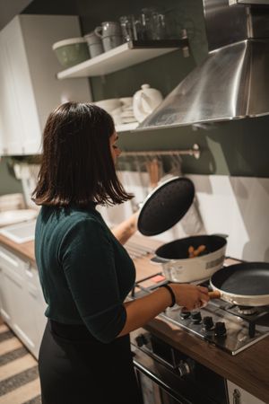Woman opening lid of pan in kitchen