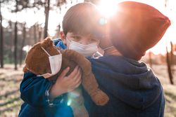 Father holding son with facemask in wood