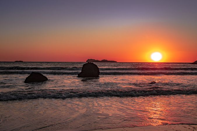 Waves coming into beach during colorful sunset