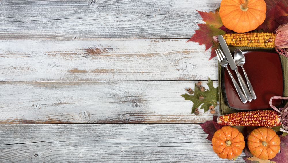 Basic dinner setting with autumn foliage and other fall decorations on rustic wooden boards