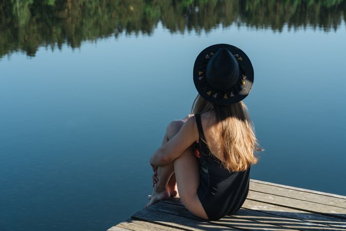 Young female sitting on pier on nature