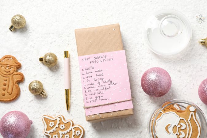 Cookies and paper with list on box on plain background, top view