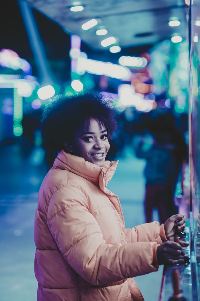 Smiling Black woman playing arcade game at night