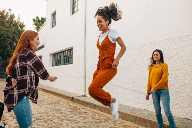 Two women holding skipping rope with a friend jumping