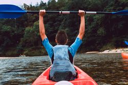 Female kayaking with paddle in raised hands