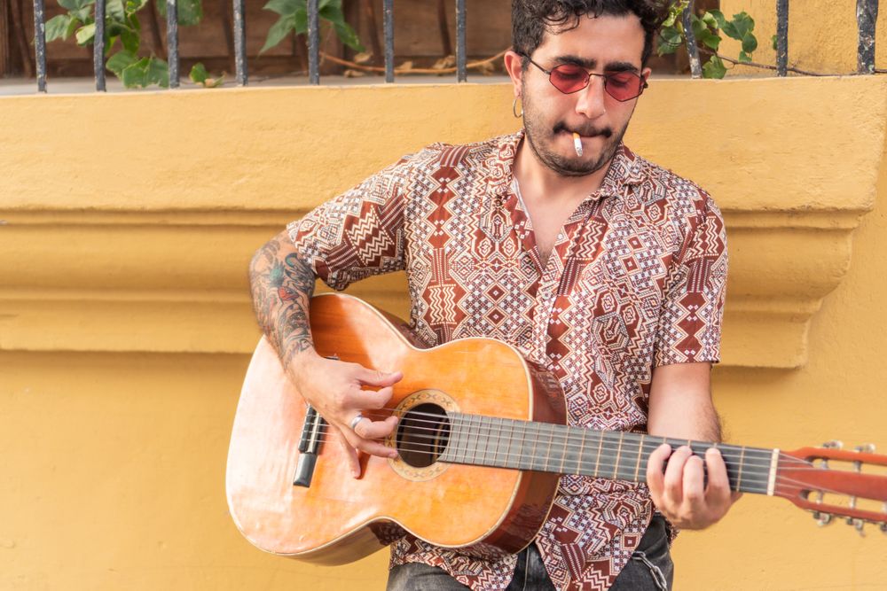 Street Musician with guitar playing guitar while smoking. Guitarist standing in the street.