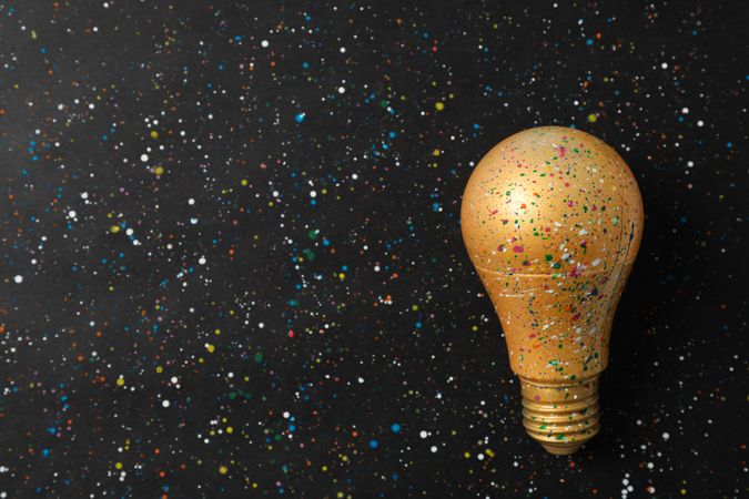 Paint splatters and spots on light bulb and dark background. Creative idea concept