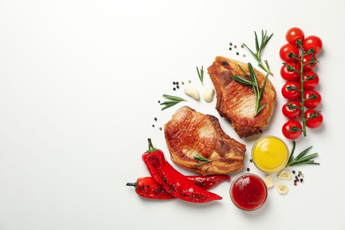 Vegetables and fried steaks on light background, top view