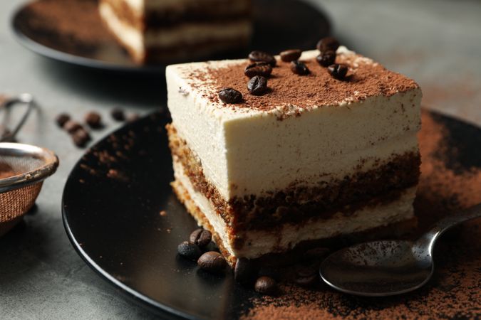 Composition with tasty tiramisu and coffee beans on gray background