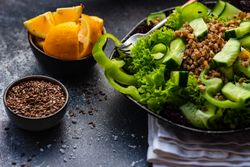 Green fresh salad with buckwheat on concrete background served with flax seed and lemon