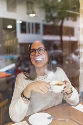 Young woman drinking hot beverage in cafe