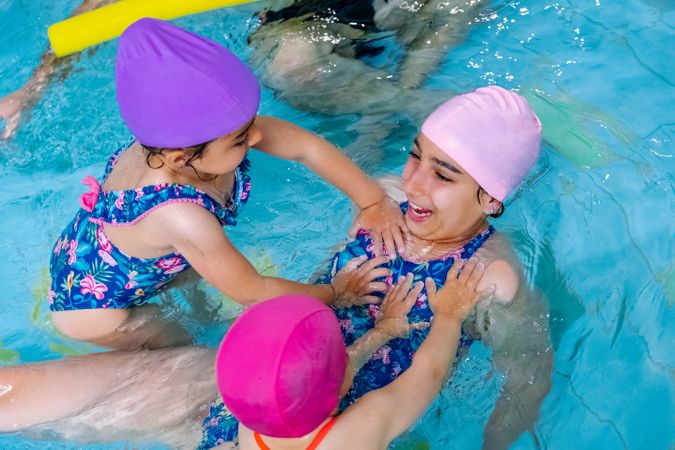Cheerful girls in hat smiling and swimming in pool in water park