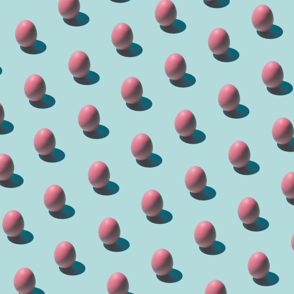 Pattern made of pink eggs on pastel blue background