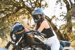 Attentive woman in helmet sitting on parked motorcycle at rural area