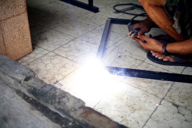 Man welding a metal frame on the ground