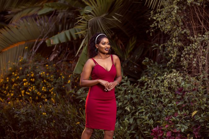 Woman in red dress standing beside a tree