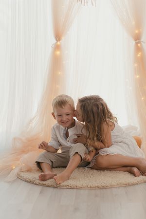 Sister kissing on cheek little brother at home